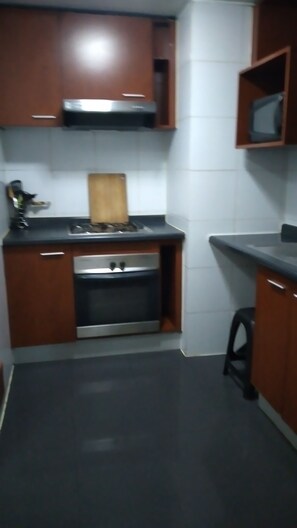 Kitchen area features a central island with a sink and stove, along with cabinetry and a microwave.