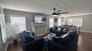 A living room with a ceiling fan, a fireplace, a TV, and a dining area with a table and chairs. - Minutes from Birmingham and Hoover! Enjoy with Family for Fun & Fellowship (Birmingham)