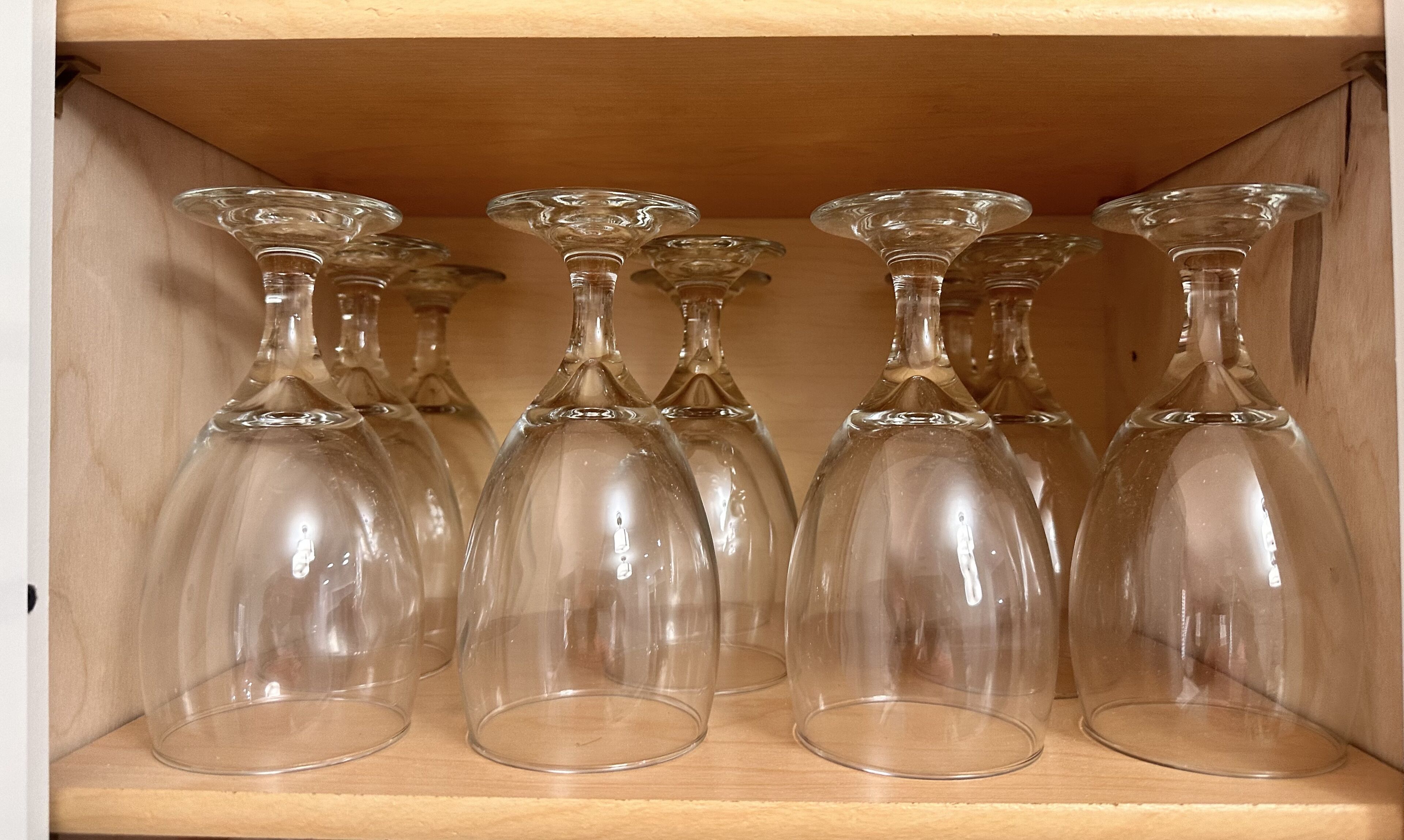 Un meuble en bois contenant plusieurs verres à vin transparents, disposés à l’intérieur.