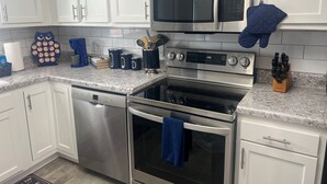 A modern kitchen with white cabinets, stainless steel appliances including a microwave, oven, and dishwasher, and a granite countertop. - Minutes from Birmingham and Hoover! Enjoy with Family for Fun & Fellowship (Birmingham)