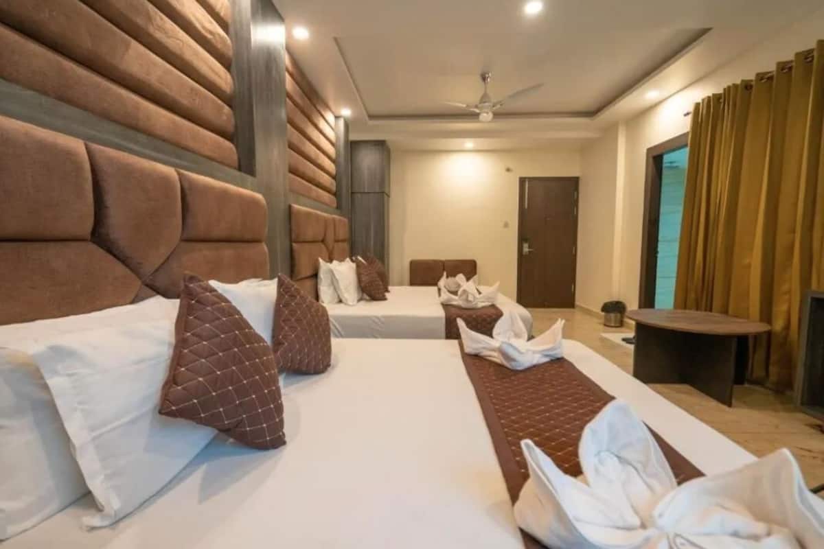 Habitación de hotel con dos camas, un ventilador de techo y una mesita.