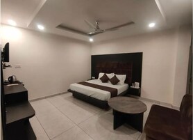 Un dormitorio moderno con una cama, un escritorio, una silla, una mesa redonda y un ventilador de techo.
