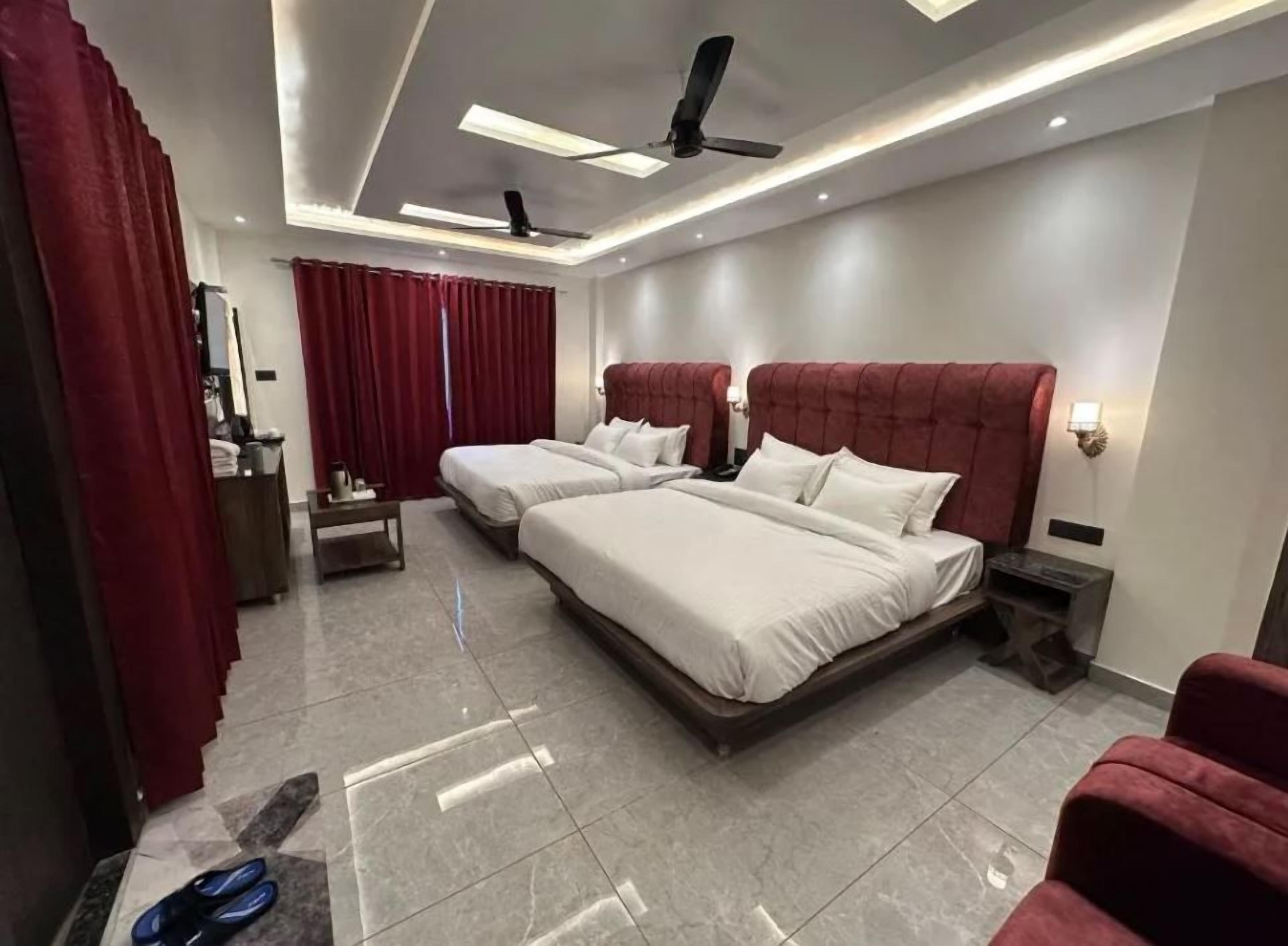 Habitación de hotel con dos camas, un escritorio, una silla y un ventilador de techo.