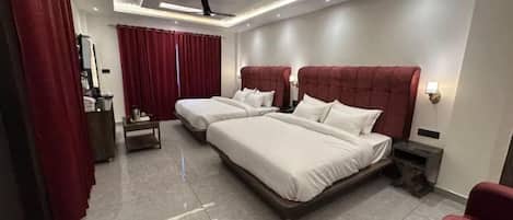 A hotel room with two beds, a desk, a chair, and a ceiling fan.