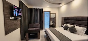 Una habitación de hotel moderna con una cama grande, una zona de estar y un televisor en la pared.