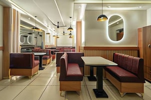 Un restaurante con asientos tipo cabina, iluminación colgante y un espejo grande en la pared.
