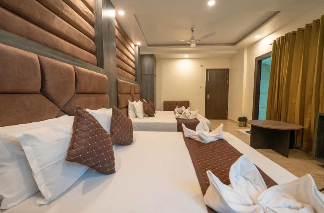 Habitación de hotel con dos camas, un ventilador de techo y una mesita.