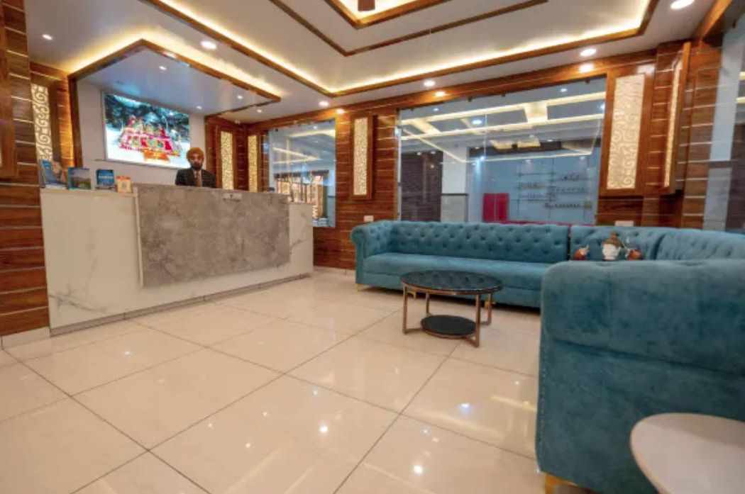 Un vestíbulo de hotel con un mostrador de recepción, un sofá azul y una mesa redonda.
