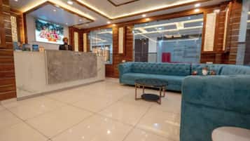 Un vestíbulo de hotel con un mostrador de recepción, un sofá azul y una mesa redonda.