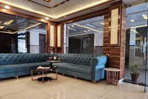 A modern lobby with a large blue sofa, a small round table, and a potted plant.