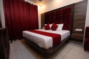 A bedroom with a large bed, red curtains, and a wooden headboard.