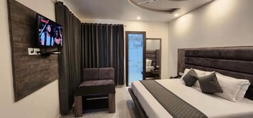 Una habitación de hotel moderna con una cama grande, una zona de estar y un televisor en la pared.