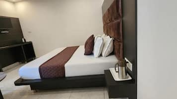 A modern hotel room with a bed, bedside table, and a TV mounted on the wall.