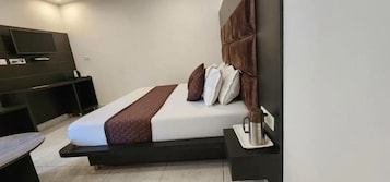 Una habitación de hotel moderna con una cama, mesita de noche y televisor montado en la pared.