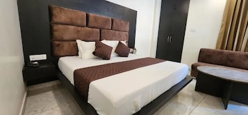 A bedroom with a large bed, a nightstand, a sofa, and a small table.