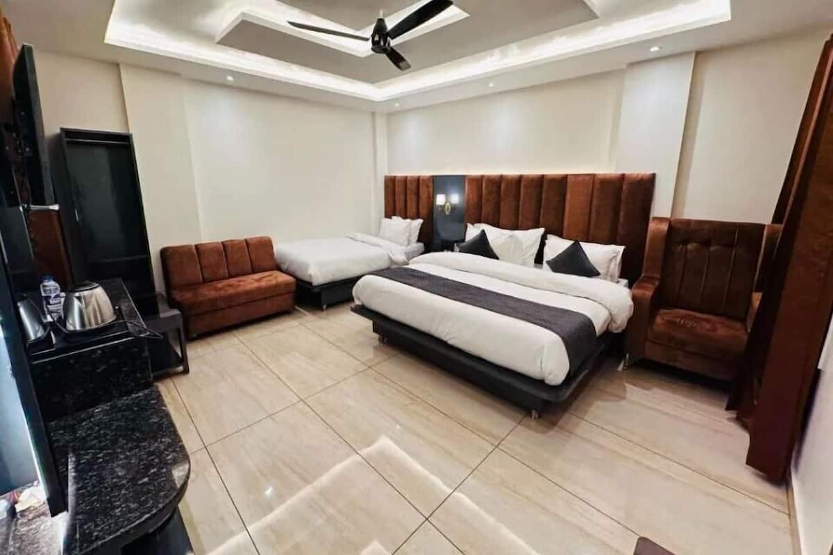 Un dormitorio moderno con una cama grande, un sofá, un televisor y un ventilador de techo.