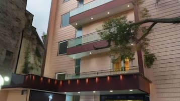 Un edificio de varios pisos con fachada moderna, un escaparate visible con letreros y balcones en cada planta.
