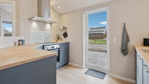 A modern kitchen with a built-in oven, a stainless steel range hood, and a large window providing a view of the outdoors. - Beautiful home in Tarm with WiFi (Tarm)