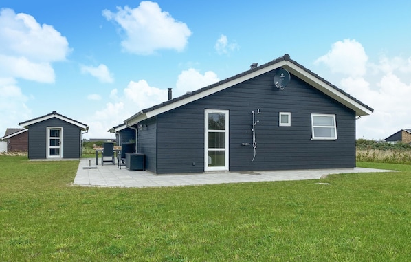 Guests can enter through the large front door with a glass panel, accessing the cozy porch area with a table and chairs.
