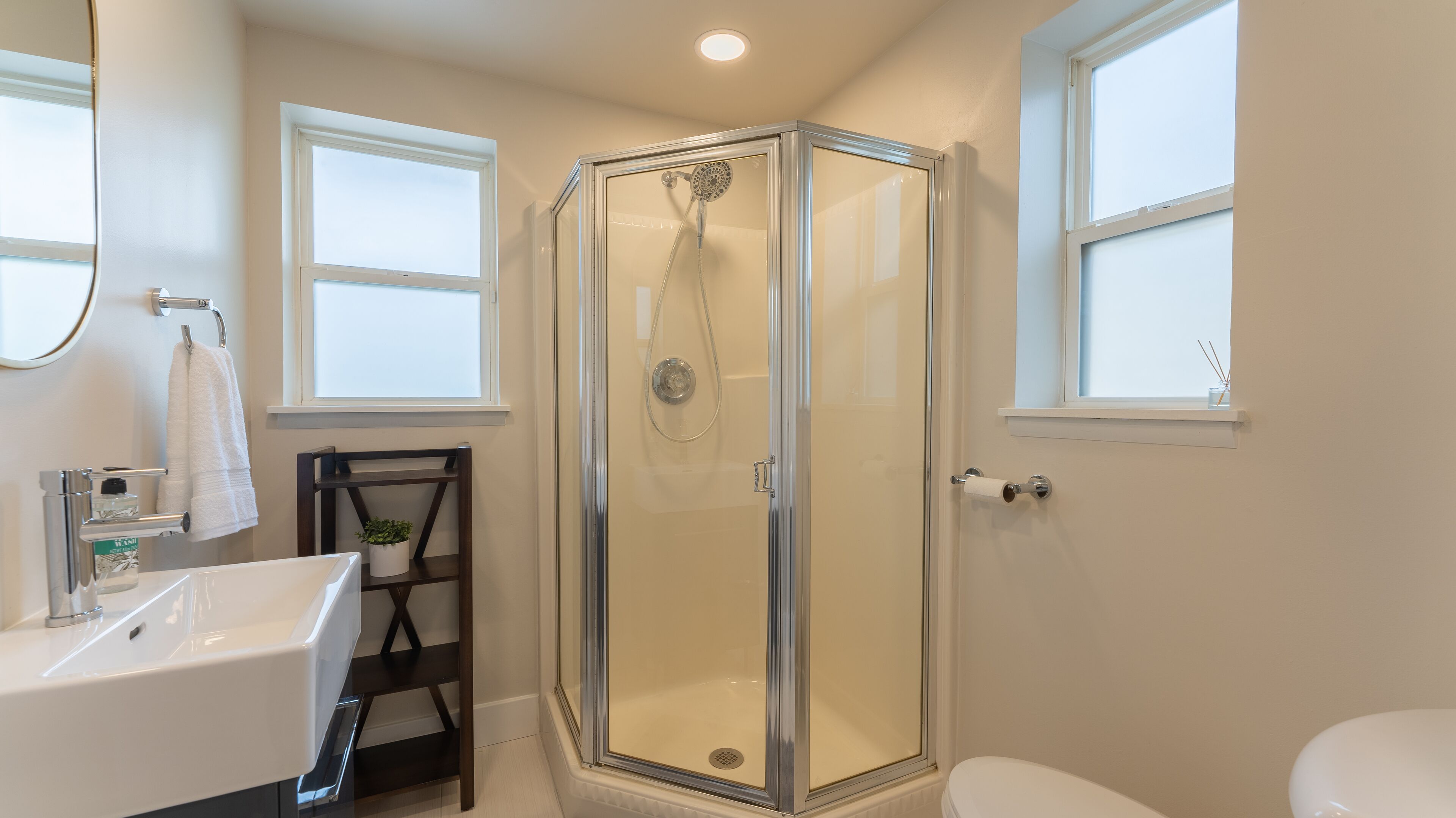 A modern bathroom with a glass-enclosed shower, a white sink, and a toilet.