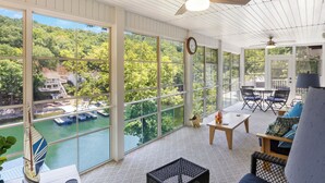 Un vaste patio couvert, doté de grandes fenêtres donnant sur un plan d’eau et un quai.