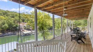 Une terrasse en bois, agréée de mobilier d’extérieur, qui offre une vue sur une rivière et une zone boisée.