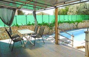 A covered outdoor area with a pool, stone wall, and a table with chairs. - Awesome home in Peroj (Peroj)