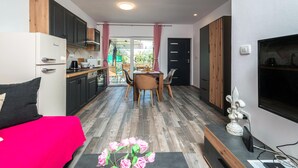 A compact kitchen with modern appliances, a dining area with a table and chairs, and a large window with curtains. - Awesome home in Peroj (Peroj)