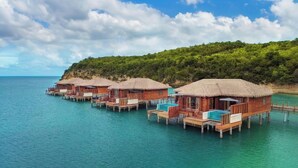 Overwater bungalows with thatched roofs, wooden railings, and a pool.