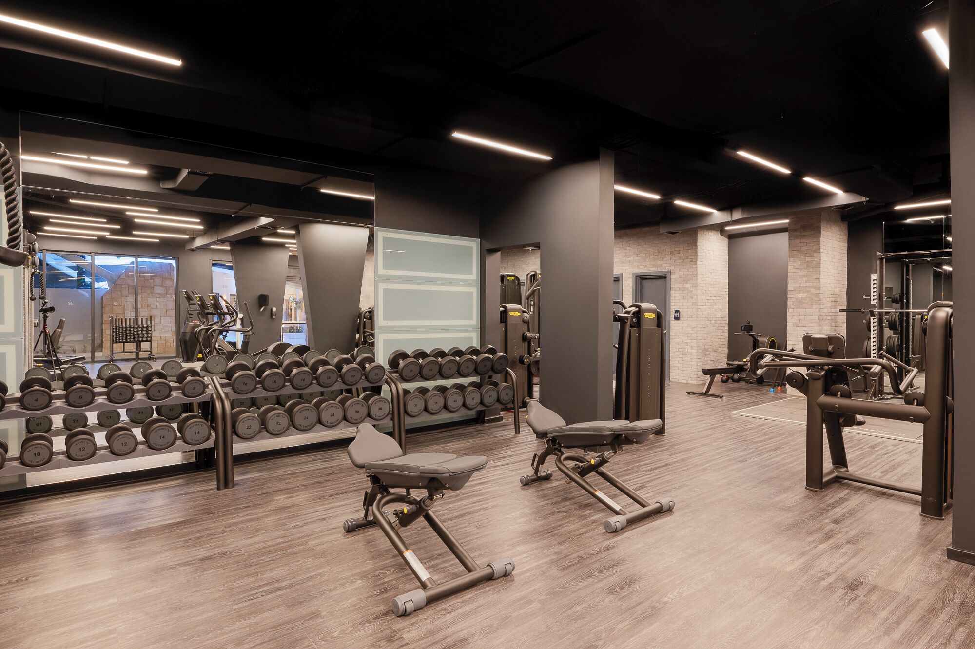 A modern gym with weightlifting equipment, dumbbells, and exercise machines.