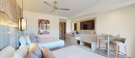 Une chambre d’hôtel moderne équipée de deux lits, d’un bureau, d’une chaise et d’un ventilateur de plafond.