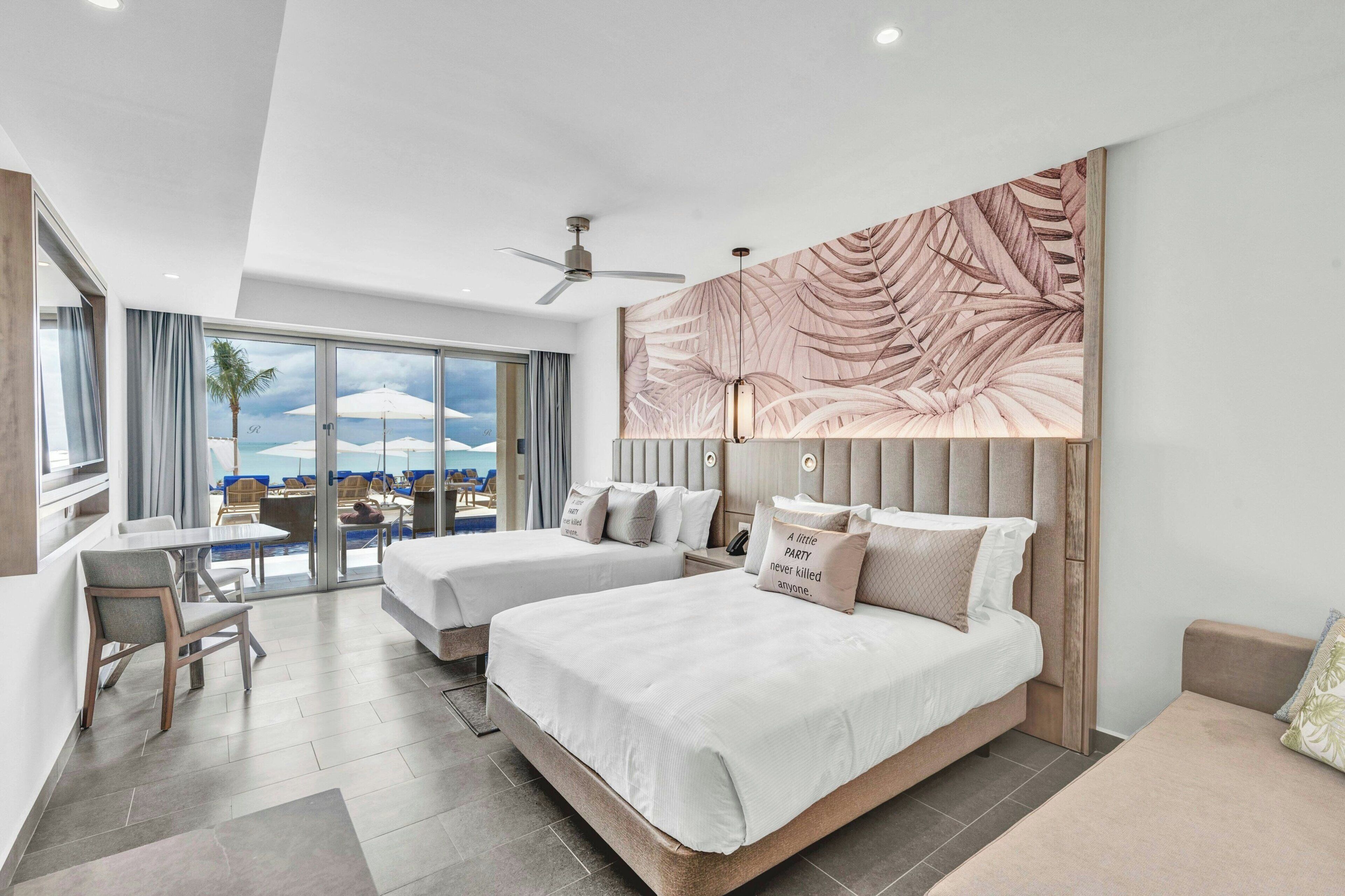 Ein modernes Hotelzimmer mit zwei Betten, einem Balkon und Blick sowie einem Deckenventilator.