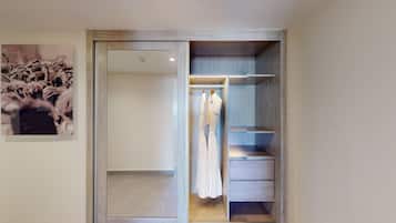 Un vestidor con estantes de madera y espacio para colgar, un espejo y un cuadro en la pared.