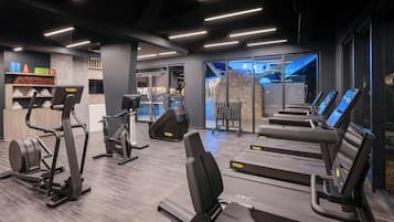 Un gimnasio moderno con cintas de correr, elípticas y bancos de pesas.