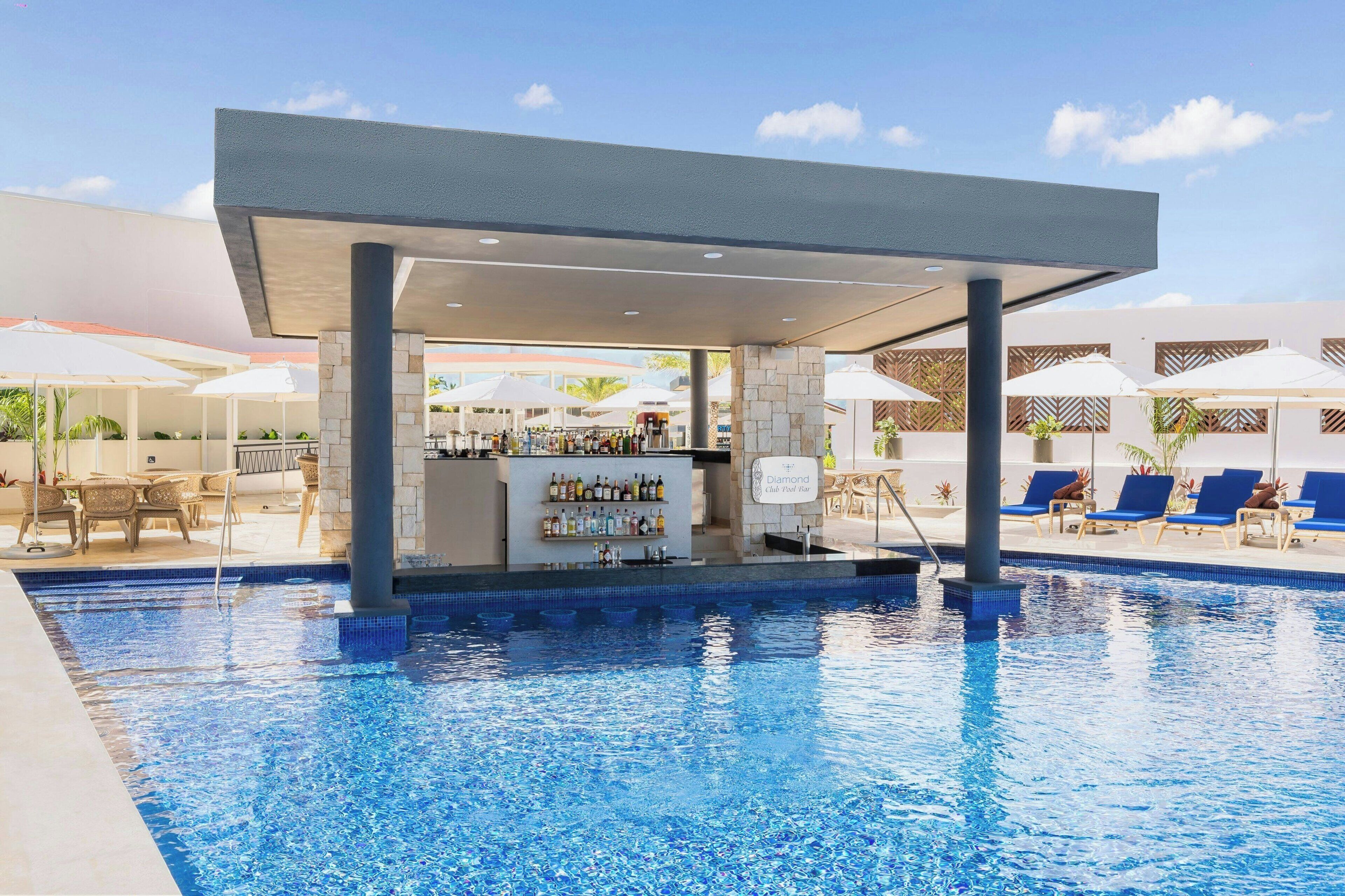 A pool area with a bar, lounge chairs, and umbrellas.