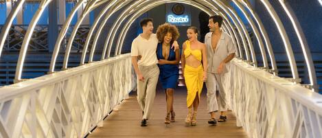 A group of people walking on a wooden bridge with a white railing and a sign that reads "Pescari".