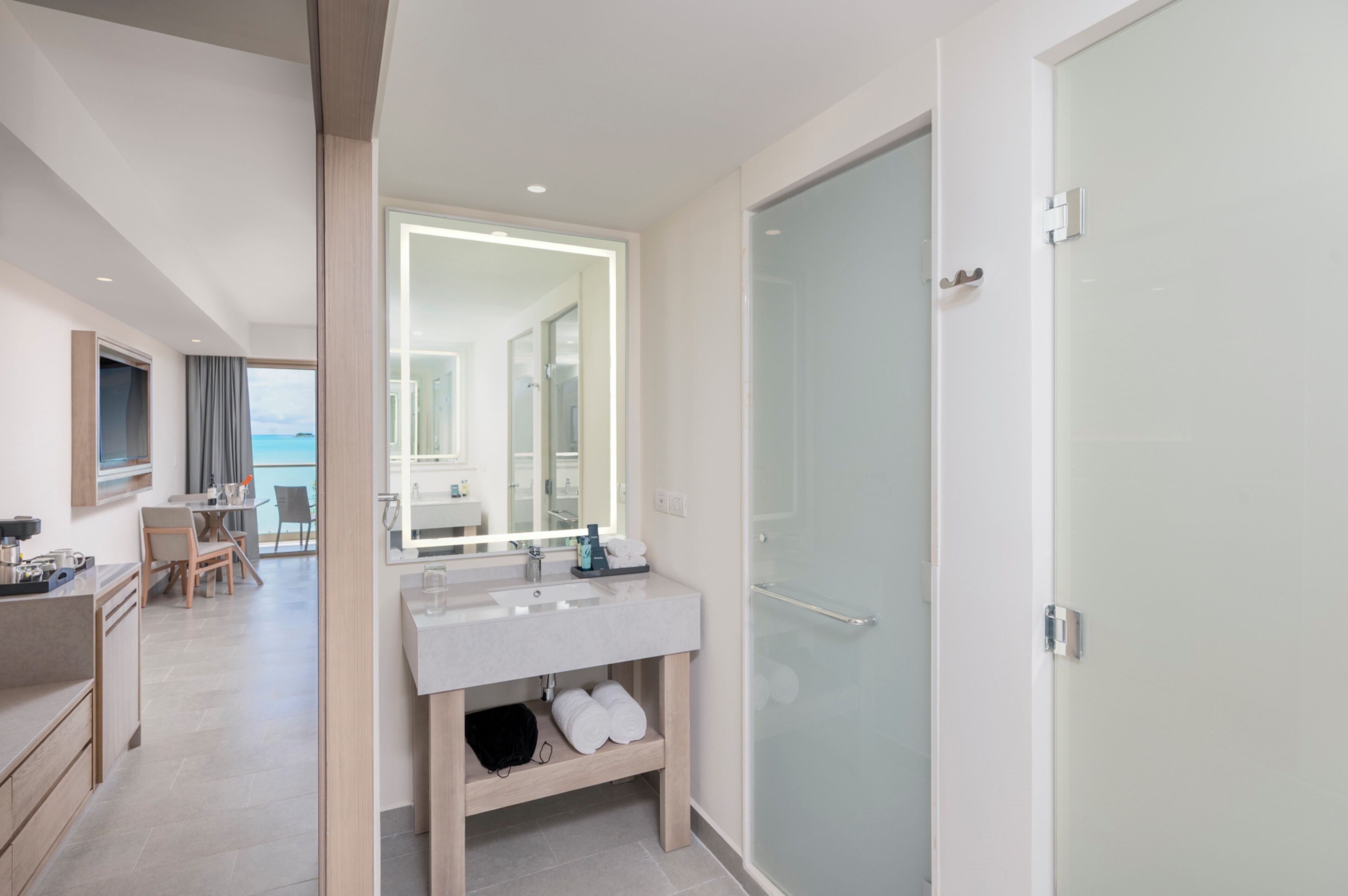 A modern bathroom with a glass shower door, a large mirror, and a vanity with a sink.