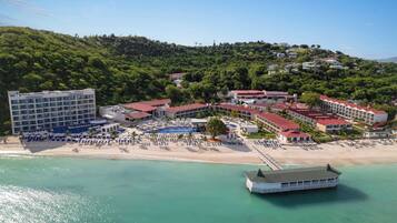 A coastal resort with multiple buildings, a beach, and a boat.