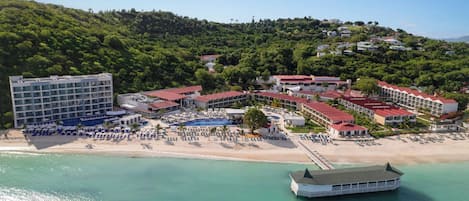 A coastal resort with multiple buildings, a beach, and a boat.