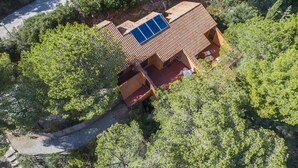 A house with a sloped roof, a solar panel, and a paved driveway.
