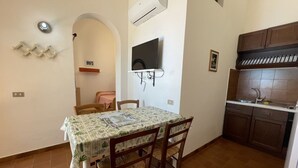 Eine kompakte Küche mit Essbereich, einem an der Wand montierten Fernseher und einer gefliesten Rückwand.