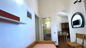 Ein Schlafzimmer mit einem Bett, einem roten Regal, einem Spiegel und einem Essbereich mit Stühlen und einem Tisch.