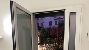 An open sliding glass door leading to an outdoor area with a bicycle, a table, and a planter. - ARCHIMEDE, 53 · Apt 3 - Monolocale con spazio esterno (Milano)