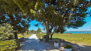 A gravel path leading to a scenic view of a coastal landscape with trees and a clear sky. - Natural Escape: Air-Conditioned T2 BIS, Pools, and Private Estate in Fitou! (Fitou)