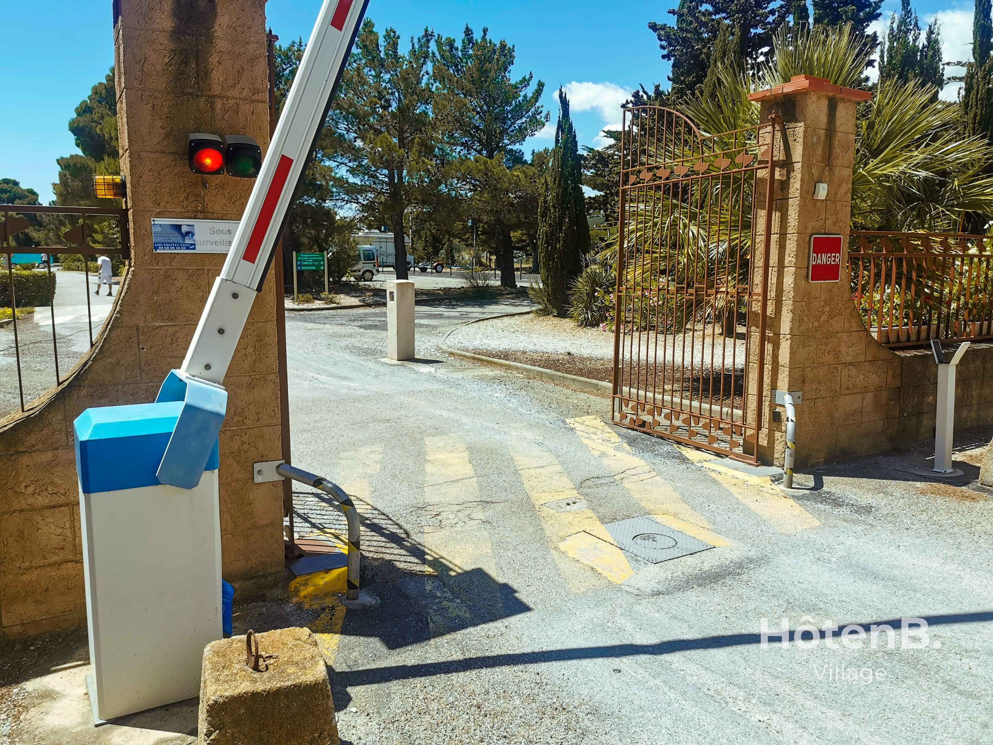 A gated entrance with a metal barrier and a pedestrian crossing signal.