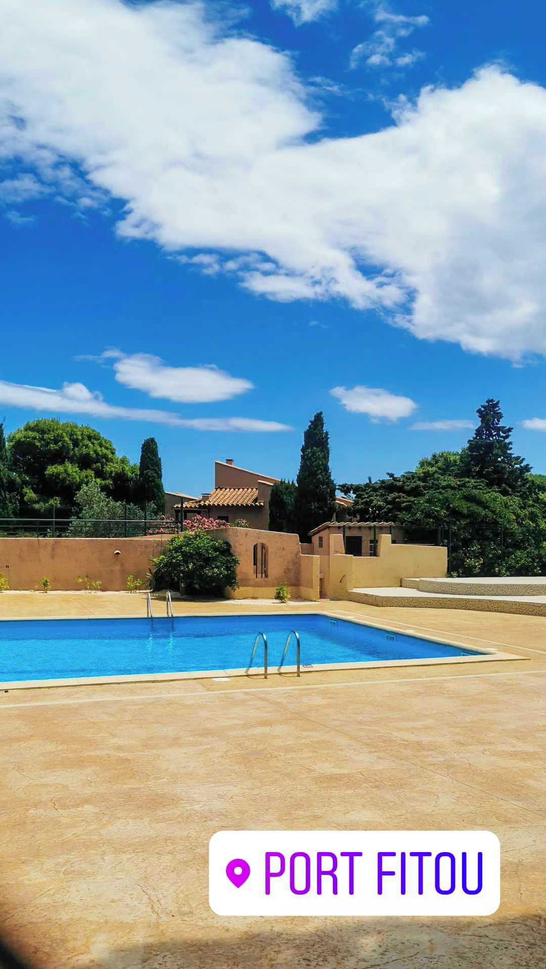 A clear blue sky with a swimming pool and a building with a tiled roof.