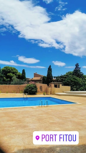 A clear blue sky with a swimming pool and a building with a tiled roof.