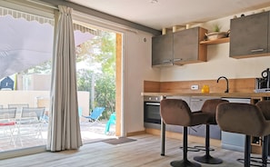 A modern kitchen with wooden cabinets, a sink, and bar stools.