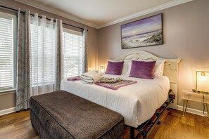 A bedroom with a bed, a bench, a bedside table, a lamp, and a painting on the wall. - Walk to Wescott Golf, Pool Access! Pondfront Home (Summerville)