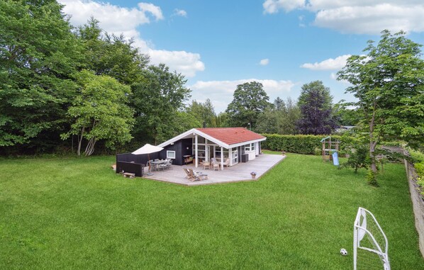 Een huis met een terras, een patio en een omheinde tuin.